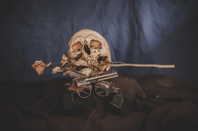 Still Life With A Cross Gun And A Skull In The Mouth With Dry Flowers.