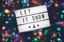 Let It Snow Sign In Lightbox Over Christmas Garland Lights In The Dark