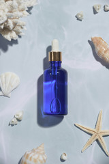 Wall Mural - Serum blue bottle with sea shells islolated on light background.