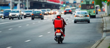 24 Hours Delivery Service From Cafes And Restaurants. Takeaway, Delivery Boy On Scooter With Red Isothermal Backpack Driving Fast. Courier Delivering Food On Motorbike To Avoid Evening Traffic Jams
