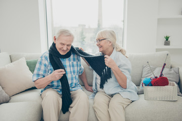 Poster - Portrait of his he her she two nice friendly lovely cheerful cheery people sitting on divan granny wrapping granddad in new scarf in light white interior living-room house indoors