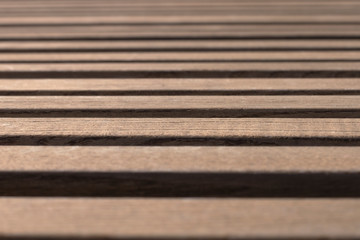 Wall Mural - Side view on brown wooden planks on a park bench on a sunny day with shallow depth of field. Abstract trendy modern texture background