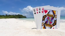 Queen Rulers. Poker With Queens. Four Cards Representing A Matriarchal Lifestyle. Tropical Beach Background, Close Up Shot With Shallow Focus