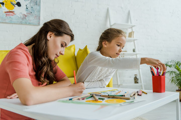 Wall Mural - selective focus of attractive babysitter drawing near cute kid in living room