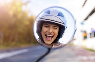 Wall Mural - Reflection of beautiful young woman in motor scooter mirror 