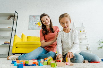 Wall Mural - selective focus of kid playing with building bricks near babysitter