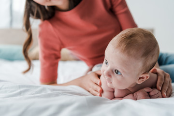 Wall Mural - cropped view of woman touching baby on bed at home