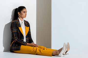 Wall Mural - young stylish woman sitting on grey and white