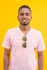 Wall Mural - Happy young African bearded man with Afro hair smiling against yellow wall