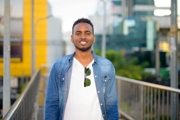 Wall Mural - Happy young African bearded man smiling on the footbridge