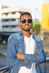 Wall Mural - Happy young African bearded man smiling with arms crossed on the footbridge