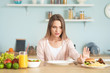 Woman refusing to eat unhealthy food in kitchen. Diet concept