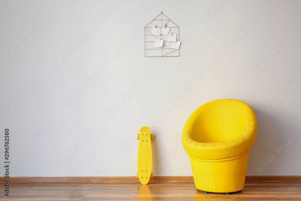 Stylish armchair with skate near white wall