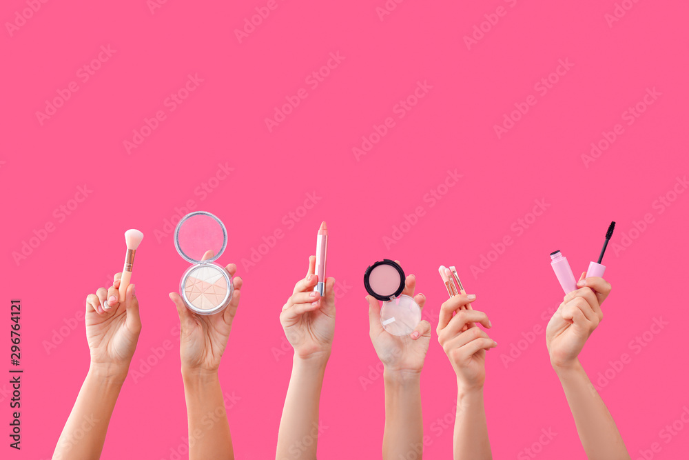 Many hands with decorative cosmetics on color background
