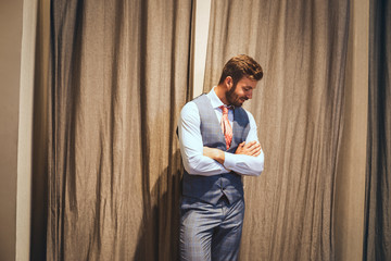 Wall Mural - Handsome young businessman smiling while standing against grey background