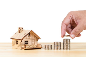 Wall Mural - Coin stack and model house with hand putting money on wooden desk on white background, mortgage concept