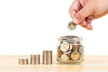 Wall Mural - Coin glass jar container and stack on wooden desk, saving concept, on white background, with hand putting money