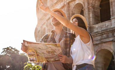 lovely couple of tourist at colosseum reading city map guide. rome, italy