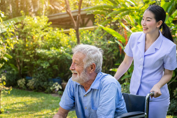 Happy nurse take care elderly man on wheelchair in garden at nursing home