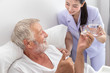 © wirojsid - Happy nurse give pills, assist, and encourage elderly senior man to eat medicine after breakfast on bed in bedroom at nursing home