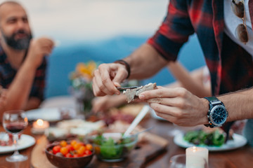 Wall Mural - Friends and family gathered for picnic dinner for Thanksgiving. Festive young people celebrating life with red wine, grapes, cheese platter, and a selection of cold meats