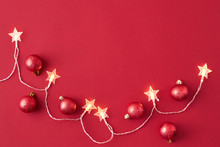 Flat Lay Frame With Christmas Garland And Red Christmas Balls On A Red Background