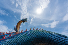 Giant Thai Naga Statue With Blue Sky Clouds In The Phu Manorom Temple, Statue Of Naka Buddha And White Large Buddha Statue At Mukdahan Province, Thailand.