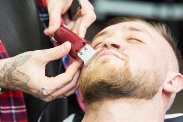 Beard care. man while trimming his facial hair cut at the barbershop