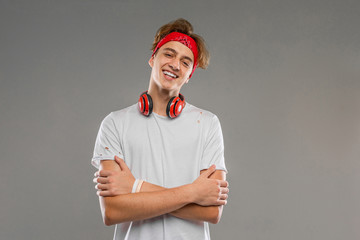 handsome teenager with headphones, young man in a light t-shirt against a gray wall background