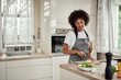 © nenadaksic - Gorgeous mixed race housewife in apron standing in kitchen and chopping mushrooms. On kitchen counter are all sorts of vegetables.