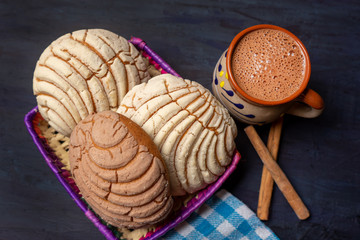 Wall Mural - Mexican hot chocolate with sweet conchas bread on dark background