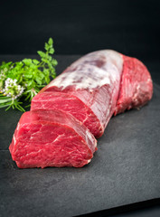 Dry aged beef fillet steak natural with a bouquet garni as closeup on black background with copy space