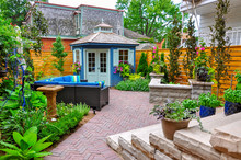 Contemporary With Traditional Elements, This Beautiful Small Urban Backyard Garden Features A Seat Wall, Red Brick Paver Herringbone Patio, High End Shed,  And Mixed Planting For Colour And Privacy.
