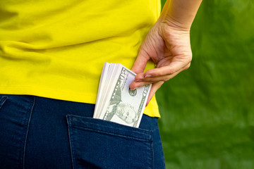 girl is pulling out a lot of american dollars out of her pocket. banknots in jeans pants back pocket