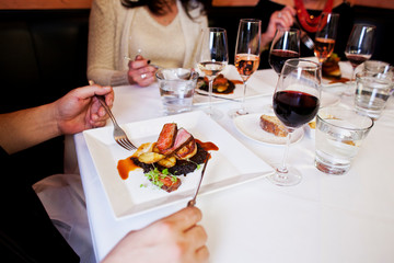 Wall Mural - friends eating dinner meal together at an elegant restaurant 