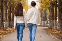 Two Girlfriends In A White Woolen Sweater And Blue Jeans