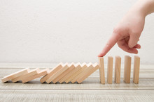 Hand Finger Stops Falling Wooden Dominoes, White Background, Domino Principle, Business Concept