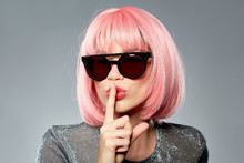 Fashion, Silence And Secret Concept - Young Woman In Pink Wig And Black Sunglasses Making Hush Gesture Over Grey Background