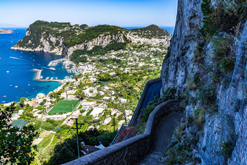 Wall Mural - Looking down the steps of the Scala Fenicia (Phoenician Steps) with Capri Marina Grande and Punta del Capo in the background, Campania, Italy