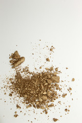 This is a photograph of a shimmery golden powder eyeshadow isolated on a White background