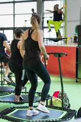 Wall Mural - Mini Rebounder Workout - People doing Fitness Exercise in Class at Gym with Music and Teacher on Stage