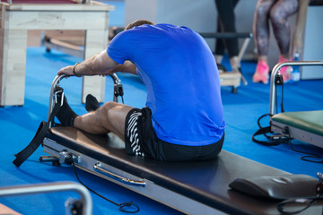 Boy sitting with his Legs Outstretched doing Stretching Before Fitness Activity in Gym