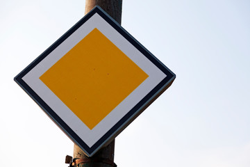 the traffic sign for the main road sits on a rusty lamp post