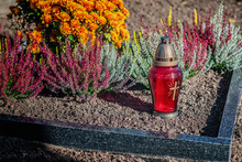 Red Lantern With Candle And Flowers On The Grave In The Cemetery