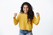 Encouraged and motivated cute african-american woman in yellow sweater raising hands up, fist pump from happiness, smiling hear good news, celebrating victory, winning huge bet, white background