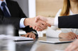 © Iryna - Businessman shaking hands with his colleague or partner above the glass desk in modern office, close-up. Unknown business people at meeting. Teamwork, partnership and handshake concept