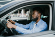 © F8  \ Suport Ukraine - Closeup portrait happy smiling young african man sitting in his new car excited ready for trip