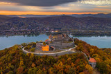 Fototapeta Na ścianę - Visegrad, Hungary - Autumn at Visegrad. Aerial drone view of the beautiful high castle of Visegrad with colorful sunset and Dunakanyar at background