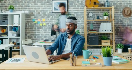 Time-lapse of serious Afro-American businessman working with laptop in office sitting at desk concentrated on work. Technology, business and people concept.