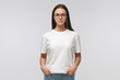 © Damir Khabirov - Young smiling woman in white t-shirt and trendy eyeglasses isolated on gray background